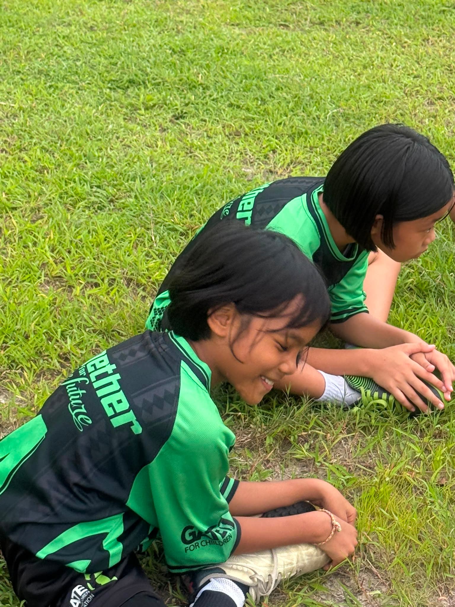 Two children laughing together on the grass
